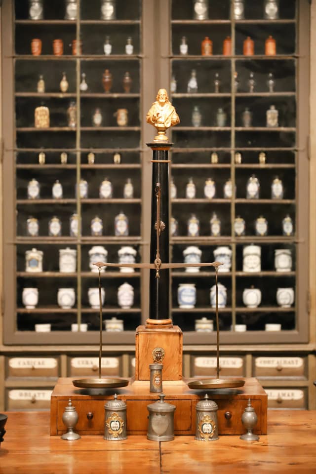 Oude apotheek met kasten vol glazen potten en een weegschaal