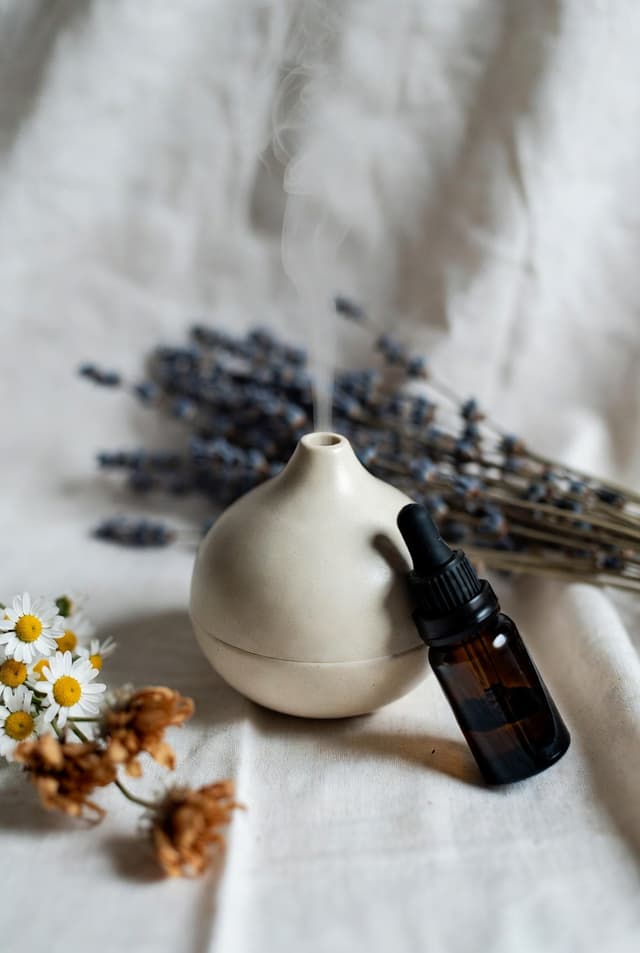 Geurverspreider met een flesje essentiële olie, lavendel en madeliefjes